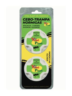 Fotografía de un blíster con dos trampas circulares blancas de cebo para hormigas. En la parte superior de la etiqueta verde y amarilla se lee “Vital Plant gel hormigas”, y en negro “Cebo-trampa hormigas”. Debajo, el texto “Eficacia - 3 meses interior / exterior”. En cada trampa aparece el logotipo “Vital Plant” junto a la silueta de una hormiga y el texto “Protege tu hogar”. A la derecha se lee “Efecto en cadena” y, en la parte inferior, “Termina con todo el hormiguero”.